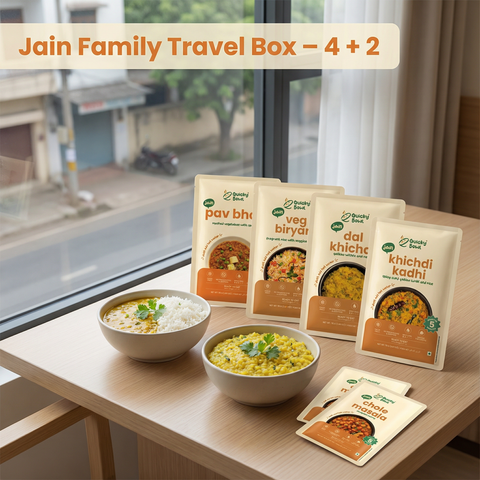 Jain Family Travel Box with food packages and bowls on a table by a window.